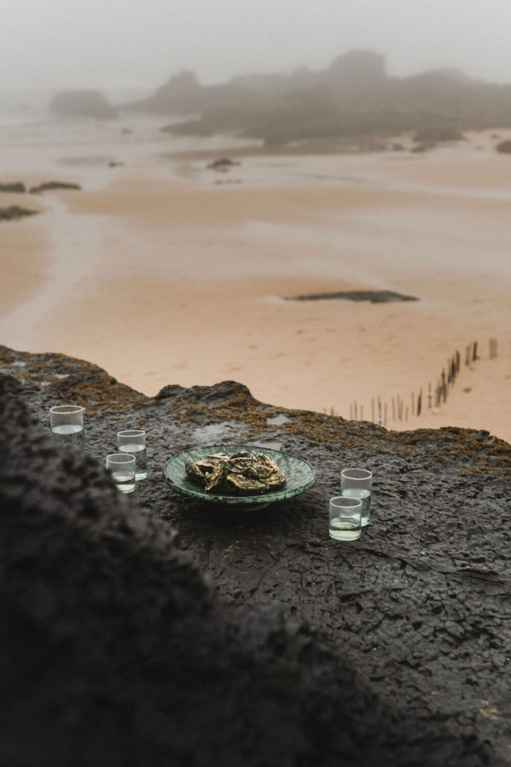 Deutsch: Austern-Dinner auf großem schwarzen Felsen am Strand Englisch: Oyster dinner on big black rock on the beach