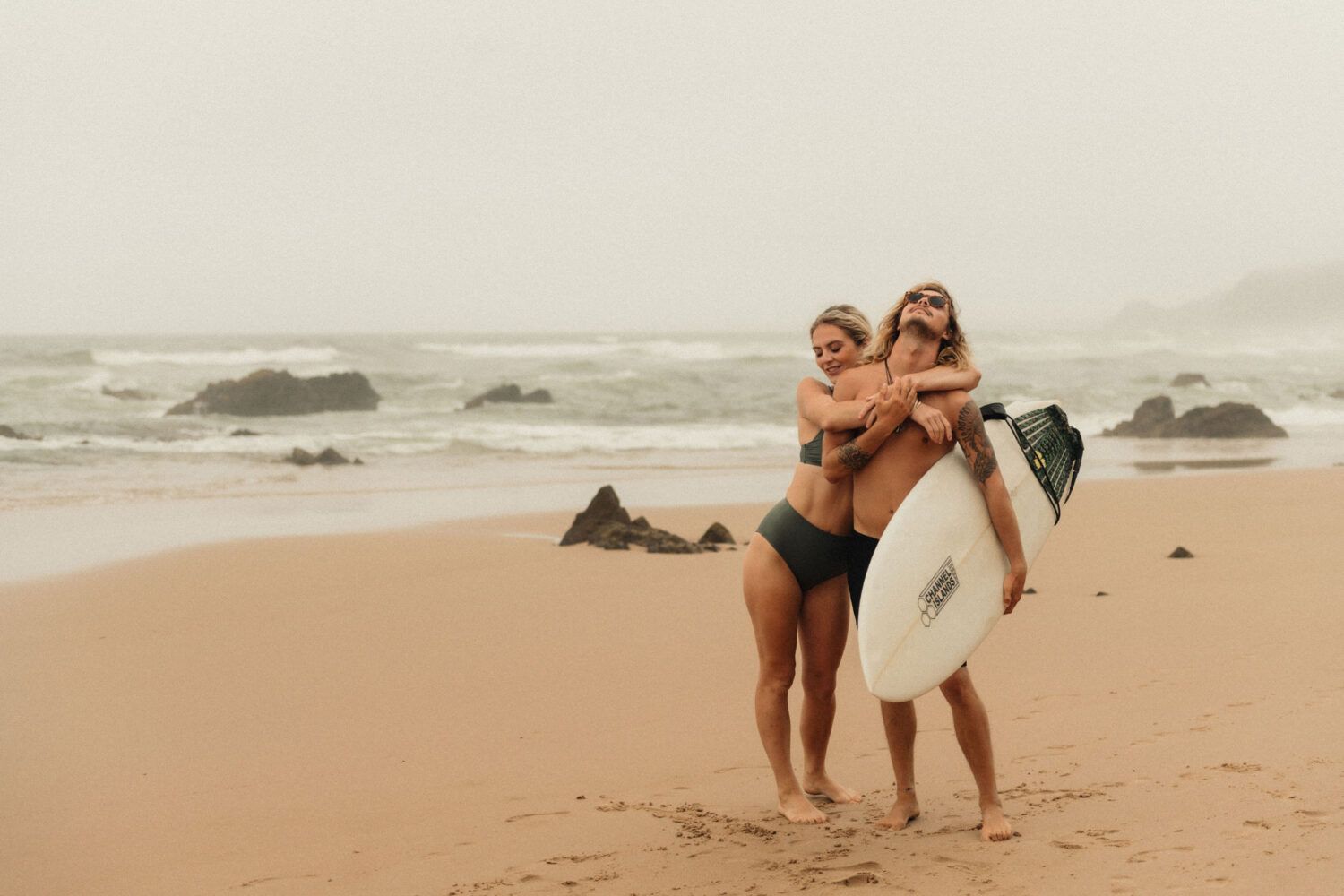 Deutsch: Lachendes Surfer-Paar am Strand Englisch: Laughing surfing couple on the beach