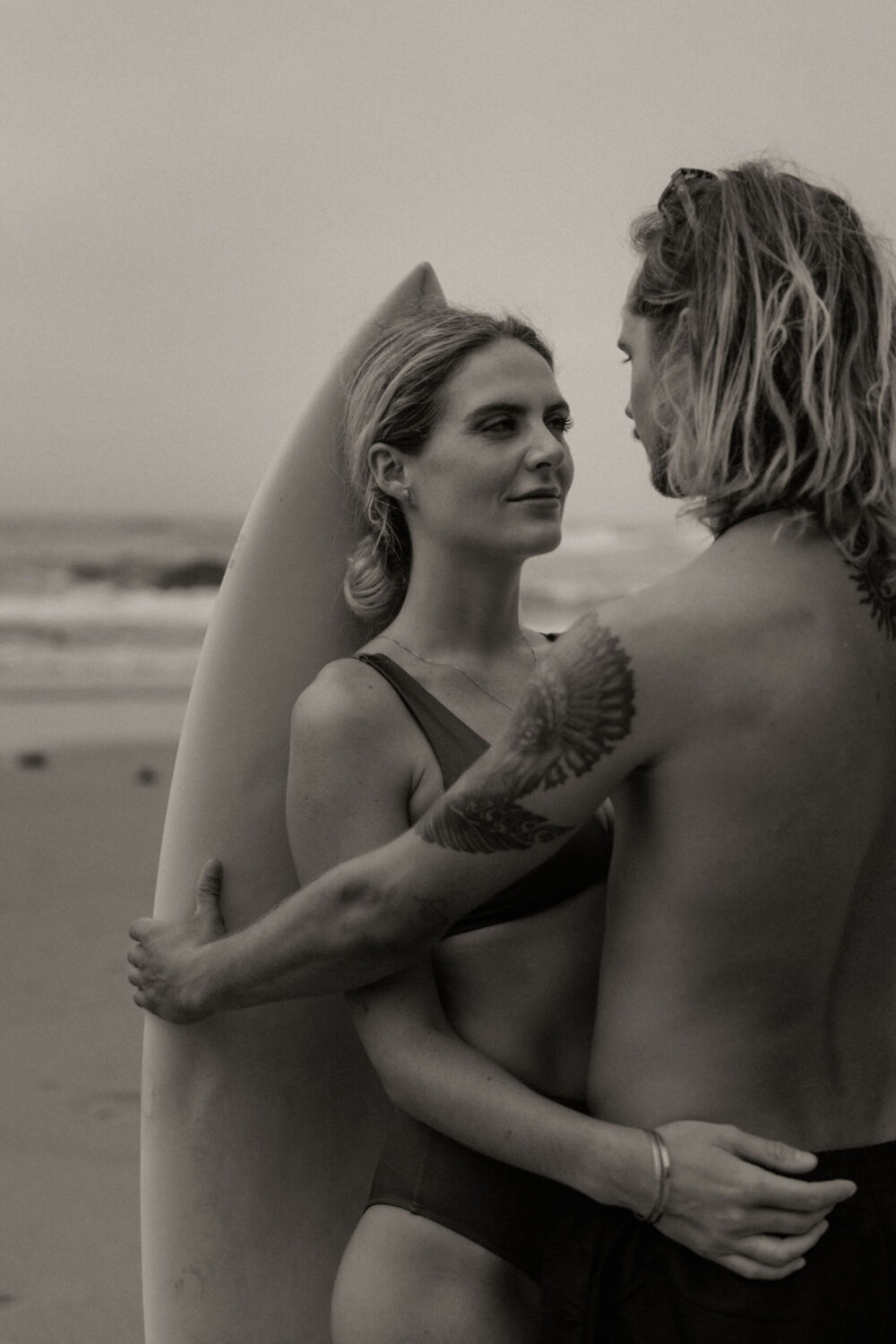 Deutsch: Surfer-Paar beim Shooting am Strand Englisch: Surfing couple during beach shoot