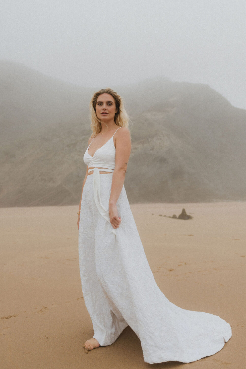 Deutsch: Braut in zweiteiligem Hochzeitskleid posiert am Strand Englisch: Bride in two-piece bridal dress posing on the beach